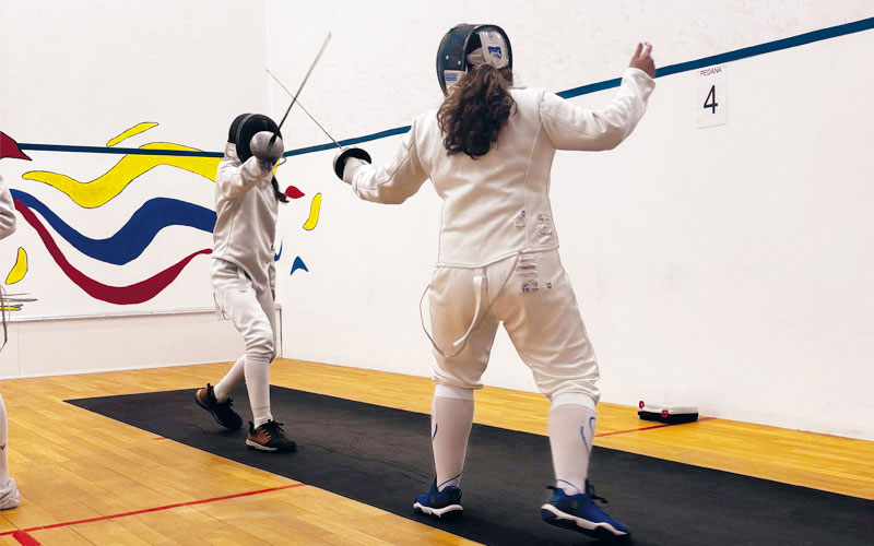 Giovani atleti durante un'intensa sessione di allenamento di scherma a Milano.