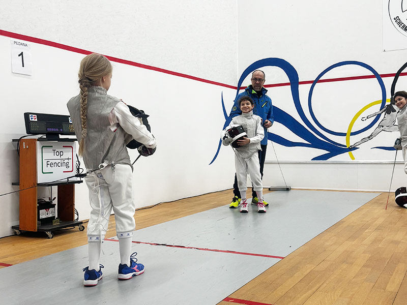 Giovane schermidore esegue un attacco sotto l'occhio vigile dell'istruttore a Milano